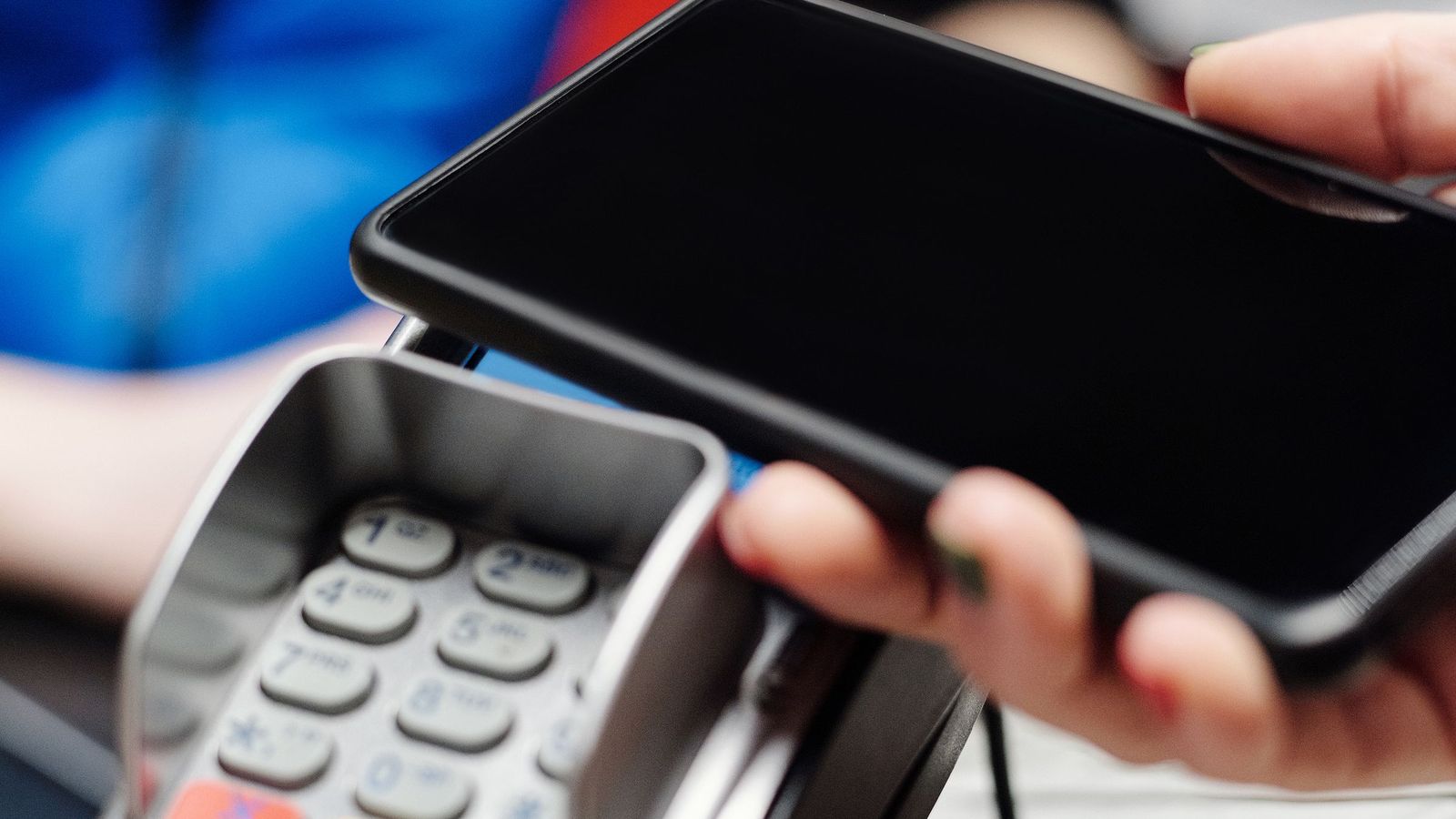 A smartphone held over a payment terminal scanning a QR code
