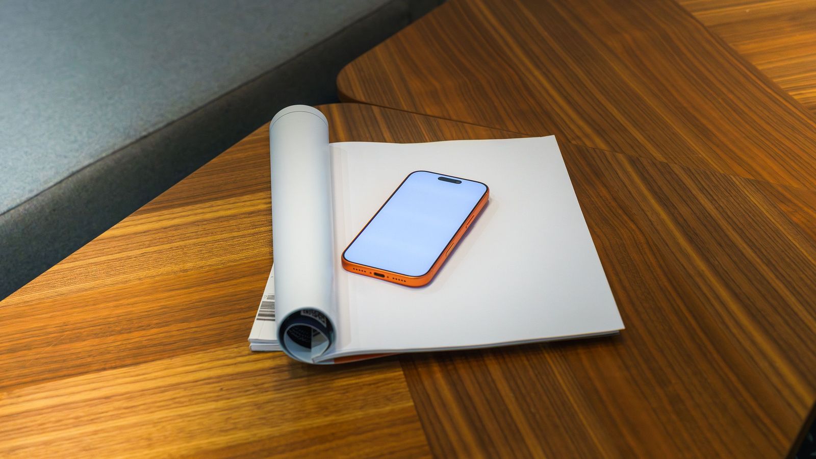 A smartphone resting on a notebook on a wooden desk